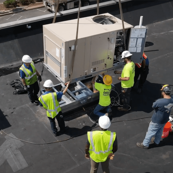 A group of construction workers working on a large unit on a roof.