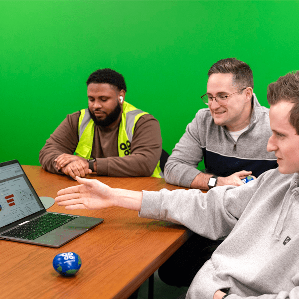 Group of men sitting around a conference table and looking at a laptop.