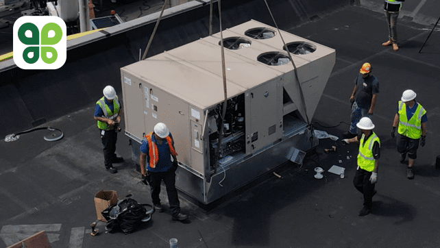 A group of construction workers lifting a large unit on a roof.