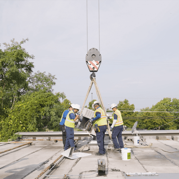 Construction workers working on a unit on top of a roof.