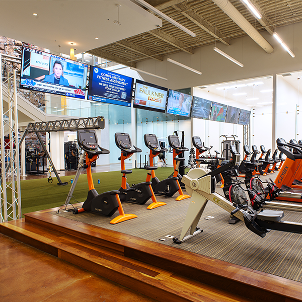 Gym with different types of workout equipment and many televisions.