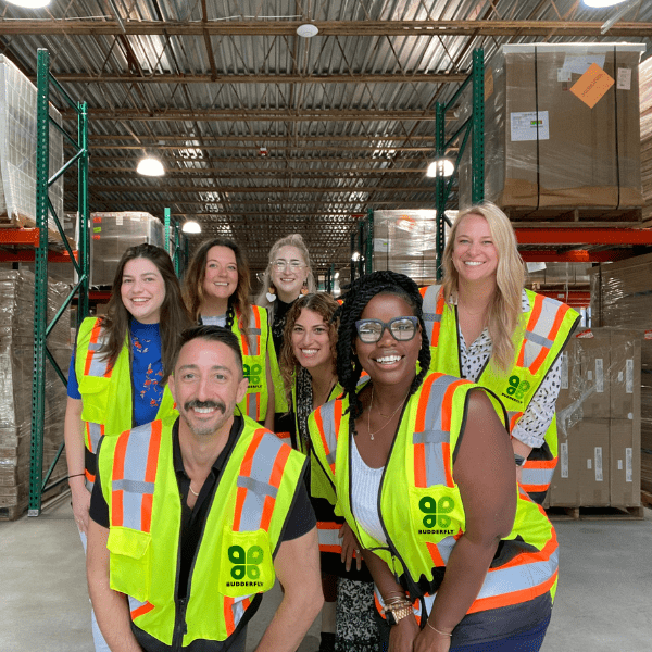 Group of people wearing Budderfly work vests and smiling.