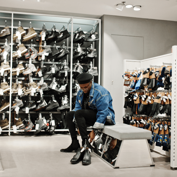 A man sitting on a bench and trying on shoes in a shoe store.