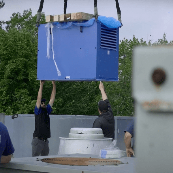 Large blue unit being lowered onto a roof.