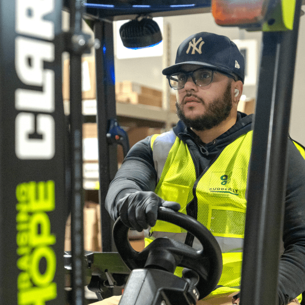 A man driving a forklift in a warehouse.