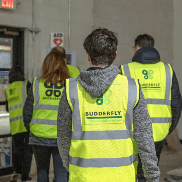 People wearing yellow Budderfly vests walk through an industrial building.